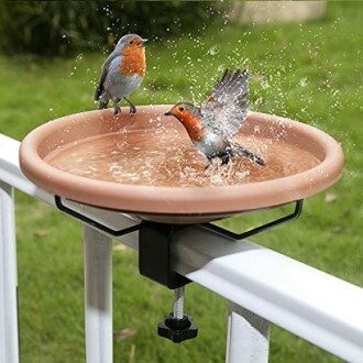 Two birds splashing in a mounted bird bath.