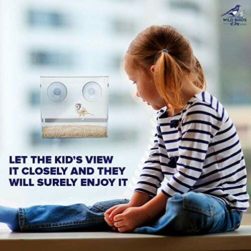 Child watching a bird feeder with a bird inside.