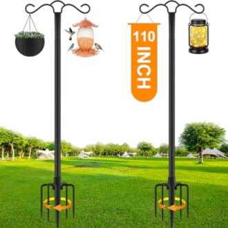 Tall garden shepherd hooks with hanging basket, bird feeder, and lantern in a grassy field.