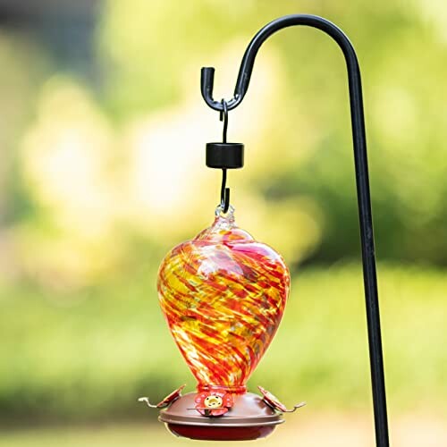 Colorful glass hummingbird feeder on a garden hook