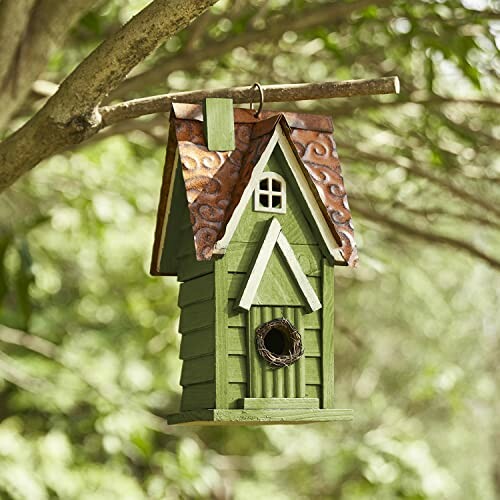 Green birdhouse hanging from a tree branch