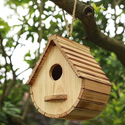 Wooden birdhouse hanging from a tree branch.