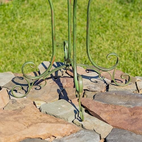 Wrought iron stand on stone surface with grass in background